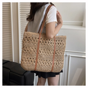 Detail showing the intricate hollow diamond floral weave pattern on the straw tote bag