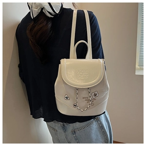 Detail view of a white patent leather mini backpack with chain and lettering on a model