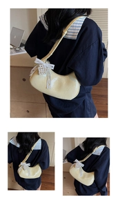 Detail of pale yellow crescent bag with delicate lace bow and pearl heart charm