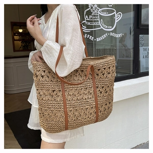 Detail of hollow-out straw weave texture and brown leather strap on large tote bag