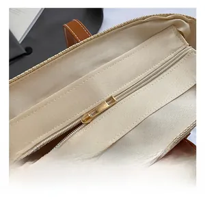 Detail eines goldenen Metallreißverschlusses an einer gewebten Strohtasche mit Lederriemen