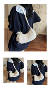 Detailed view of white crescent bag with soft leather texture and pearl cluster charm
