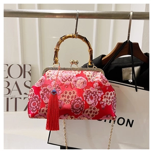 Detailed view of Chinese embroidery bag with bamboo handle, gold clasp and red tassel