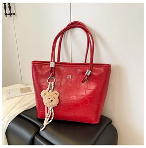 Vue détaillée du sac cabas rouge motif crocodile avec boucles argentées et bijou d'ours