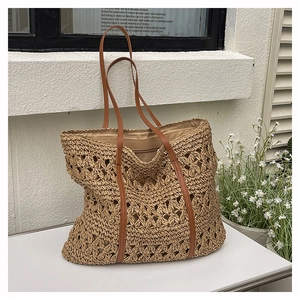 Detailed close-up of woven straw tote bag with brown faux leather straps and fabric lining