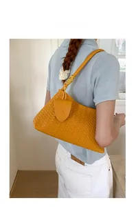 Detail of hand-woven bright yellow leather underarm bag with refined strap craft