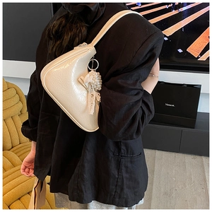 Dettaglio della borsa a spalla in pelle bianco crema con fiocco in pizzo e perle decorative