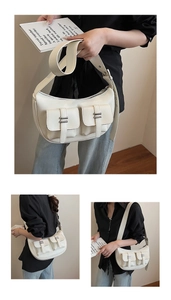 Detailed view of ivory white crescent bag featuring dual front pockets and silver buckles