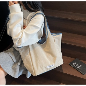 Detail of minimalist tote bag with navy blue trim and branded label on a wooden step