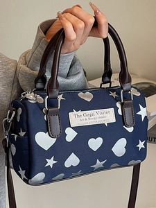 Borsa Boston blu con stampe di cuori argentati e manici in pelle marrone su modella