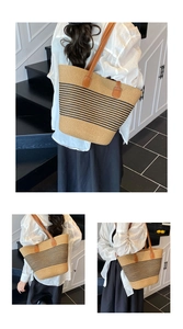 Detail der großen gewebten Strohtasche mit schwarzen Streifen und braunen Kunstlederriemen