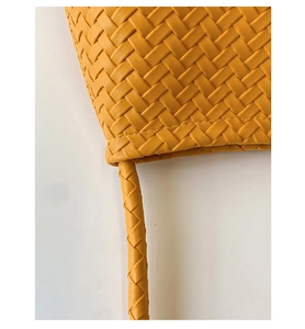 Close-up of yellow woven leather bucket bag with Intrecciato pattern and handle detail