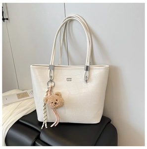 Détail du sac cabas blanc à texture crocodile avec logo argenté et ours en peluche