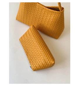 Detail of yellow woven underarm bag and matching zipper pouch in elegant weave pattern
