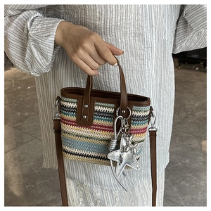 Detail of colorful woven tote with leather handles and a silver star pendant accessory