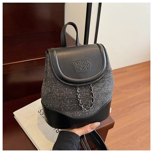 Close-up of mini backpack showing grey tweed texture, silver rivets, and woven chain strap