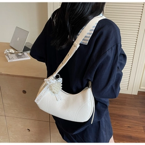 Detail showing white hobo bag with pearl heart charm and lace bow on a textured leather finish