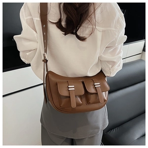 Detail view of a brown faux leather crossbody bag with utility pockets and silver buckles