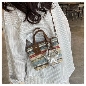 Close-up of rainbow woven tote bag with brown leather handles and starfish charm detail