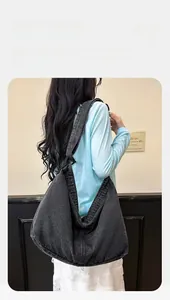 Detail einer großen hobo-tasche aus schwarzem gewaschenem denim mit breitem schultergurt