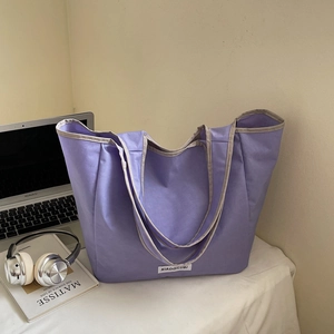 Detail view of purple canvas tote bag with gray trim on office desk lifestyle scene