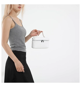 Detail of white lychee texture leather handbag with dual metal zippers and sturdy top handle
