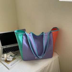 Detail view of a large color-block tote bag in purple, mint green, and orange canvas fabric