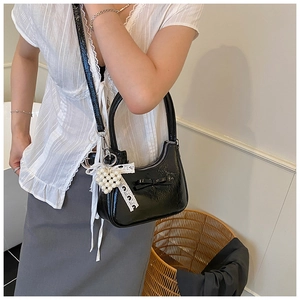 Dettaglio borsa hobo in vernice nera con ciondolo a cuore in pizzo e perle e fiocco