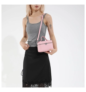Pink textured leather crossbody bag detail with top handle and adjustable strap on model