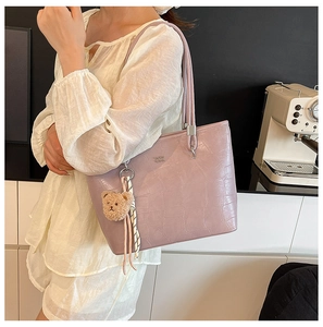 Détail d'un sac cabas violet lavande à texture crocodile avec un charmant ours en peluche