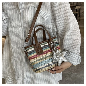 Detail of colorful woven mini tote bag with brown leather trim and silver star charm