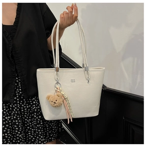 Détail du sac cabas blanc à motif crocodile avec breloque ours et foulard en soie