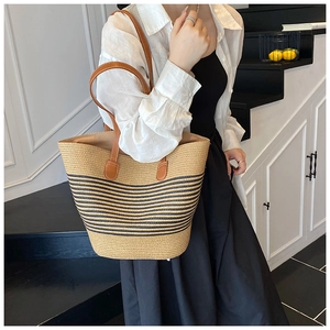 Detailansicht der gewebten Strohtasche mit schwarzen Streifen und braunen Ledergriffen