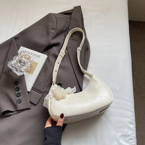 Detail of hobo bag with pearl heart charm and lace ribbon on cream pleated leather