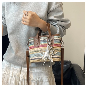 Detail of colorful woven straw bag featuring brown leather straps and a silver star charm