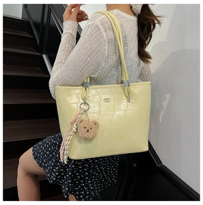 Vue latérale d'un sac cabas jaune à motif crocodile avec un ours sur un mannequin