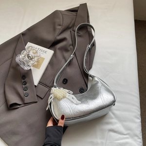 Detail of silver metallic crescent bag featuring pleated texture and pearl heart charm