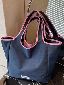 Large dark blue nylon tote bag with pink trim and handles in a modern lifestyle setting