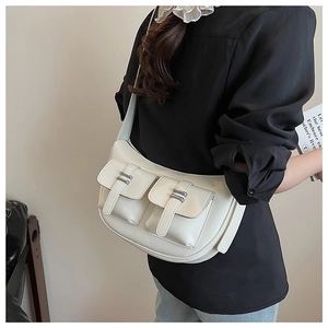 Detail of soft cream white leather shoulder bag featuring dual pockets and silver buckles