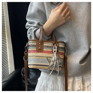 Detailed view of striped woven straw bag with brown leather handles and star pendant