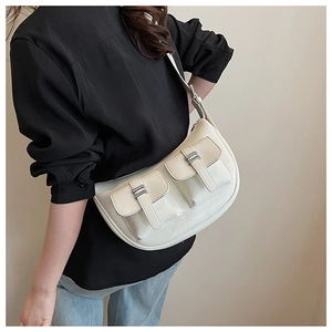 Detail view of cream hobo bag featuring twin front pockets and silver buckle hardware