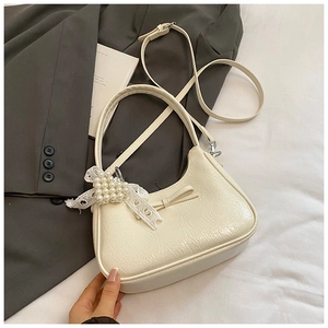 Dettaglio della borsa bianco crema con trama in pelle pieghettata e ciondolo a cuore