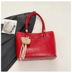 Détail du sac cabas rouge à texture crocodile avec un pendentif ours en peluche mignon