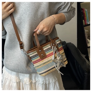 Close-up of colorful rainbow straw woven bag with brown leather handles and starfish charm