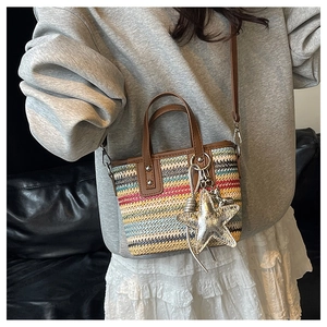 Detail of colorful striped woven handbag with brown leather straps and silver star pendant