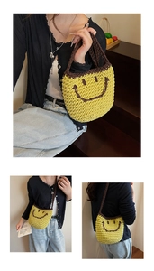 Detail of hand-woven yellow straw bucket bag with smiley face and brown contrast handle