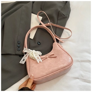Borsa a tracolla rosa a pieghe con fiocco e ciondolo di perle su sfondo in tessuto morbido