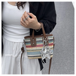 Street style view of multi-color striped woven bag with a silver star pendant