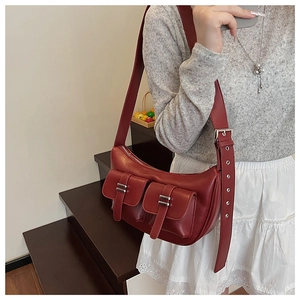 Side view of a dark burgundy soft leather crescent tote bag worn on a model's shoulder