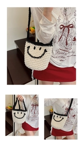Close-up of hand-woven straw bucket bag with smiley face pattern and black shoulder straps